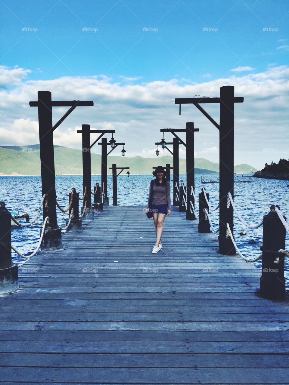 Fashionable woman standing on wooden pier over lake