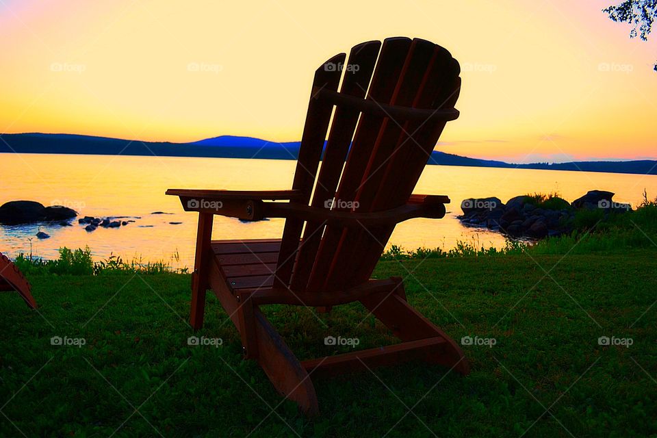 Golden glow Adirondacks. Adirondack chair against the golden glow of sunset at the lake