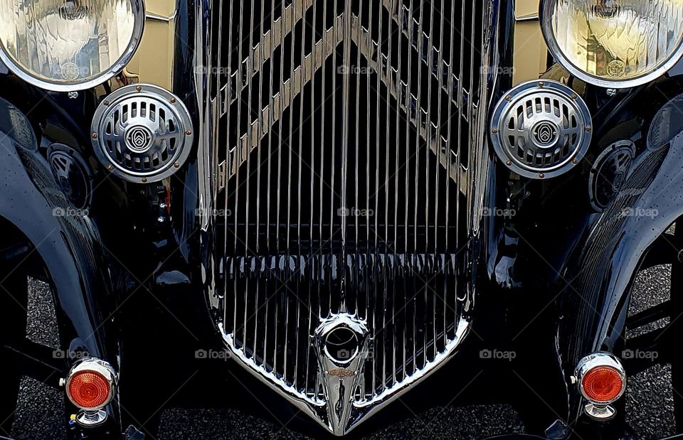 The front of a black, cream and burgundy Citroën Rosalie showing the grill and front lights at Cherbourg car show