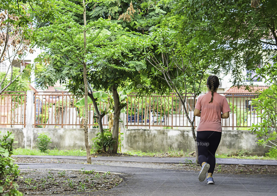 Asian women are jogging in the Park Background tree.