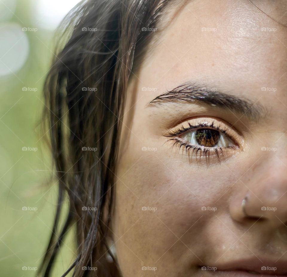 Soraya - her face and hair still damp from wild swimming, sunlight through trees illuminates one eye, reflecting her natural surrounding