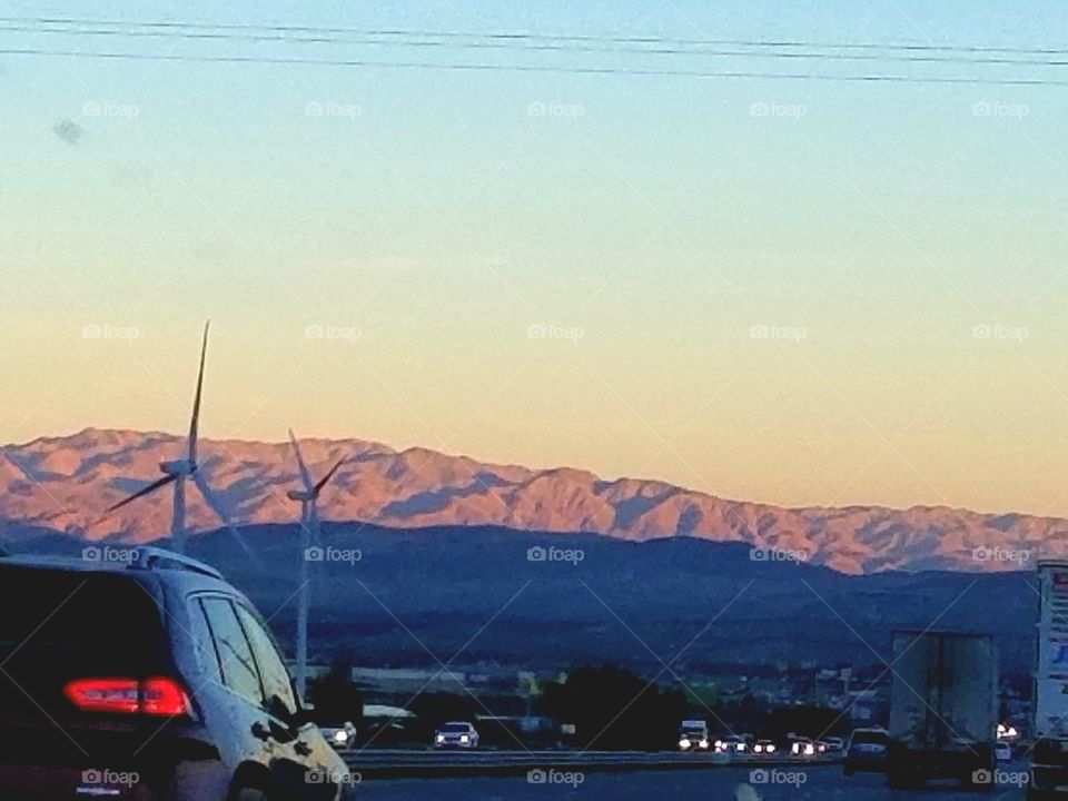 Close up of car tail light with wind turbines in the distance