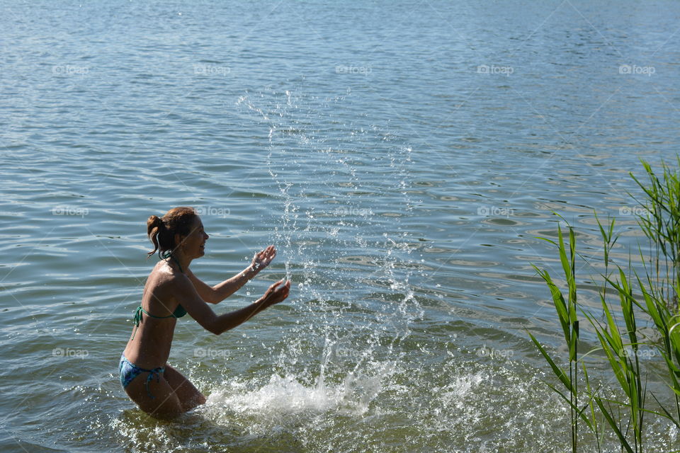 woman in swimsuit in the water lake splash summer time, summer heat