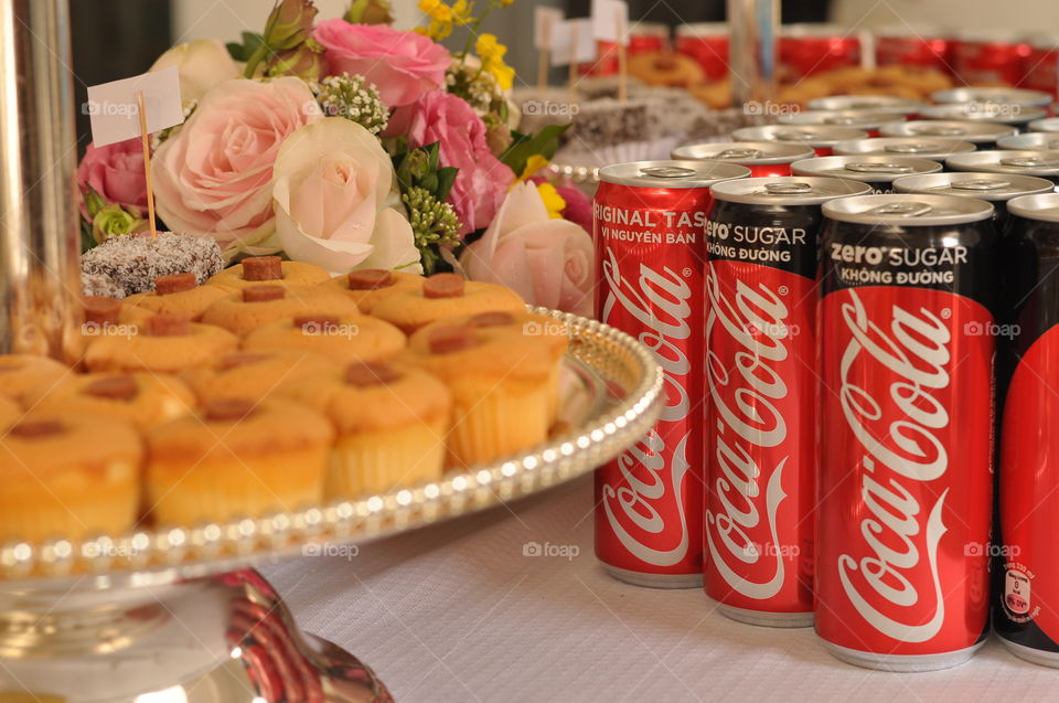 Coca-Cola cans like rows, cake and flowers on table