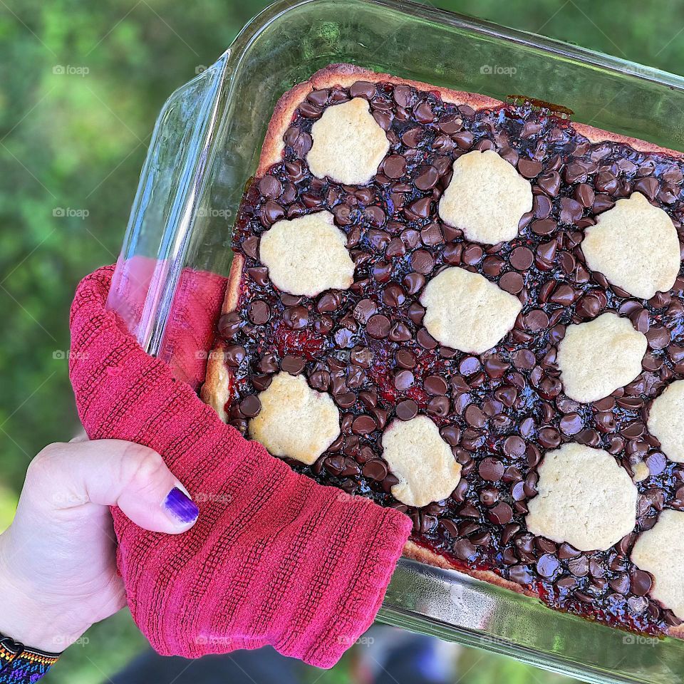 Raspberry chocolate bars, baking at home, homemade desserts, woman’s hand holding tray of desserts 