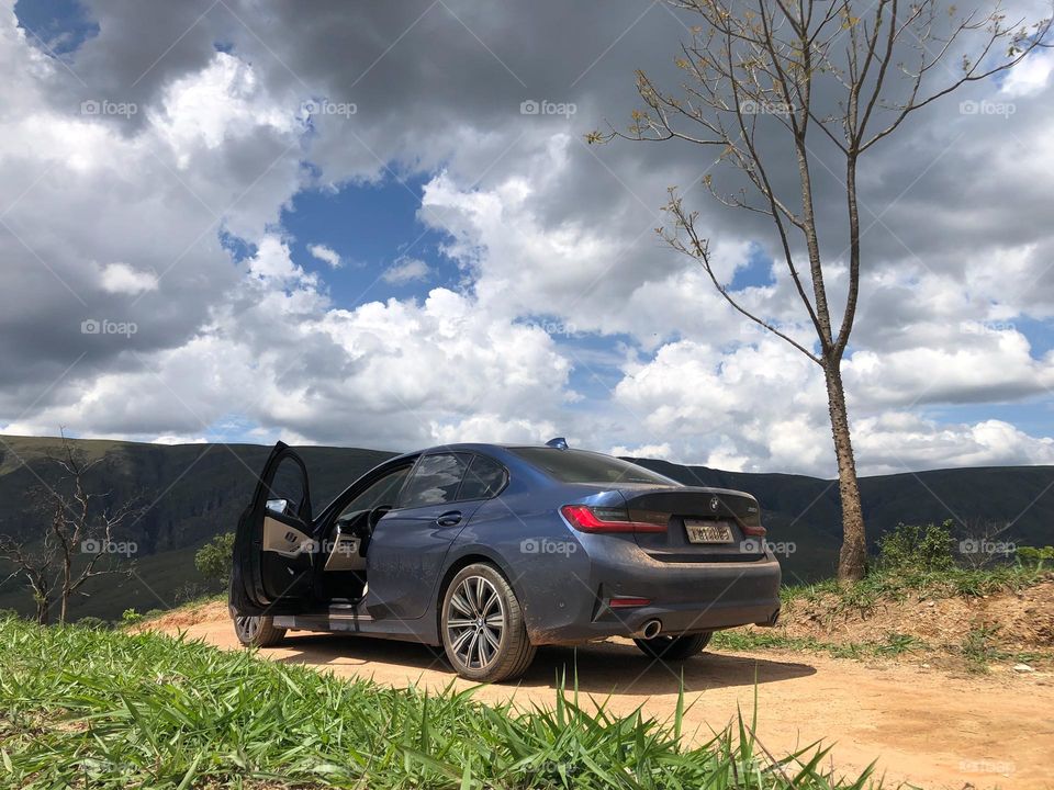 Blue car on a dirt road close to the mountain 