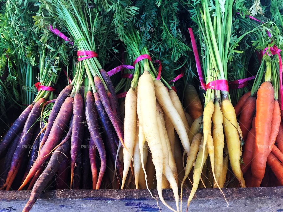 Bunches of different coloured heritage carrots on a market stall