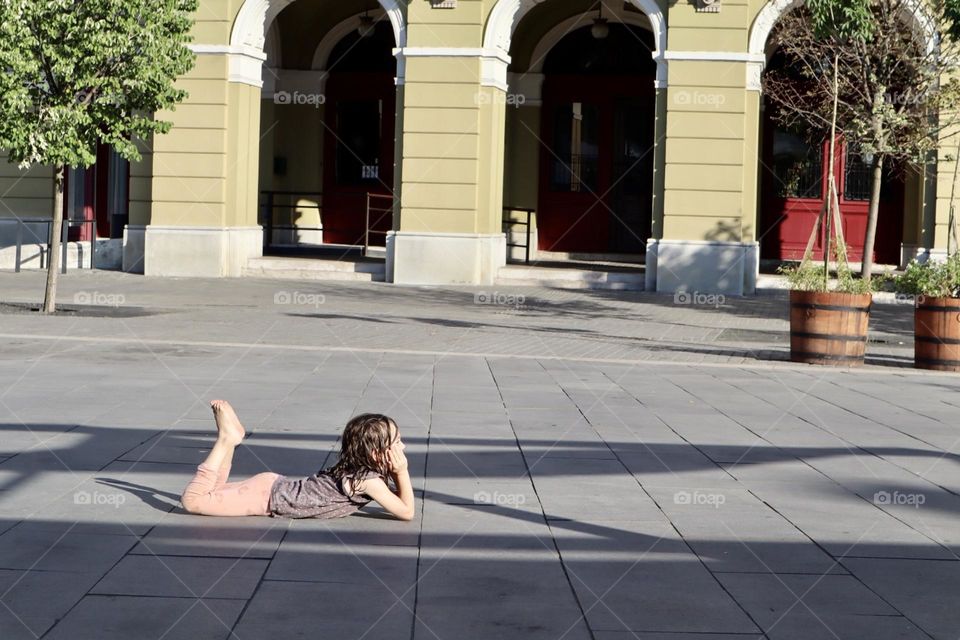 Girl getting dry at sun on pavement square 