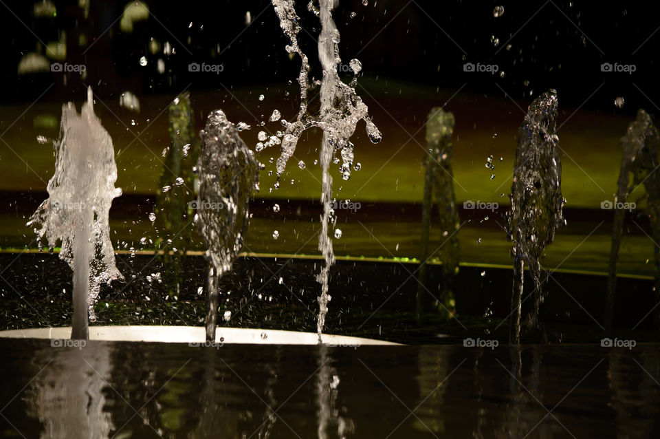 Beautiful stop motion dancing  water background with stop motion of fountains pouring water that look like people walking away next to burst of dancing water surreal photography 