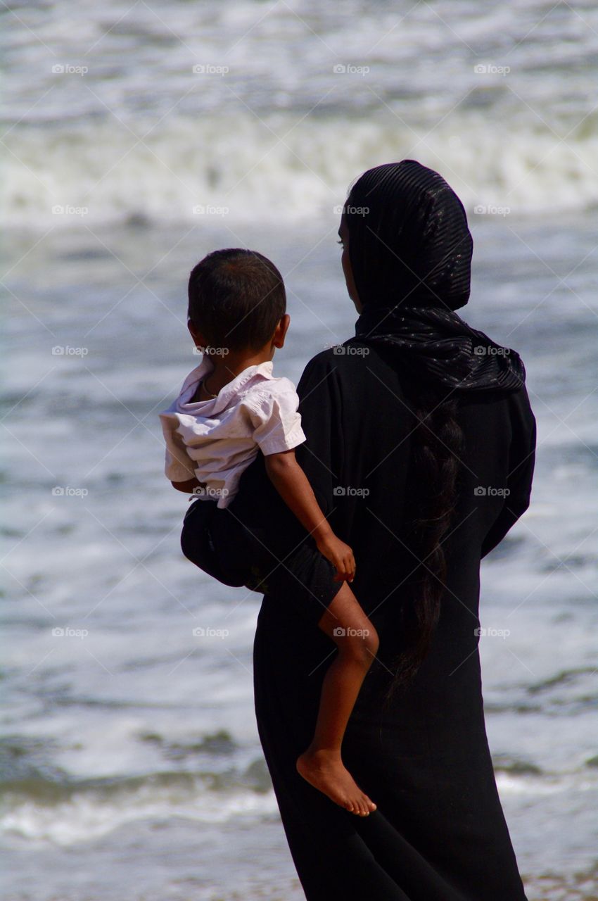 Muslim woman , mother . India , chennai , marina beach. Muslim woman with son , looking on the ocean 