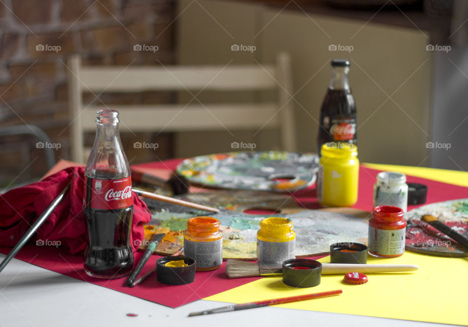 Coca-Cola bottles and colorful painting materials on the table