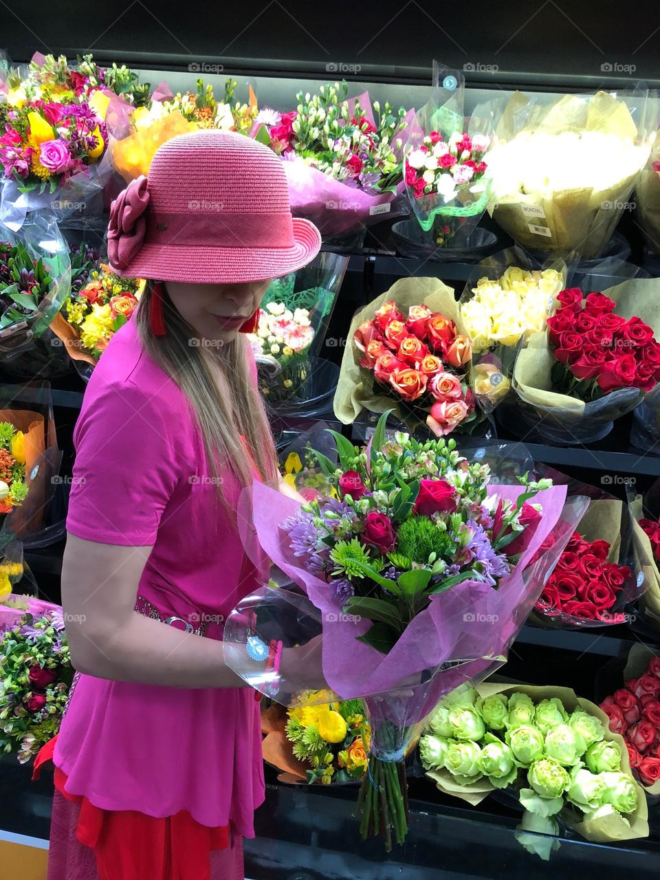 Woman wearing hot pink clothing selecting a flower bouquet.