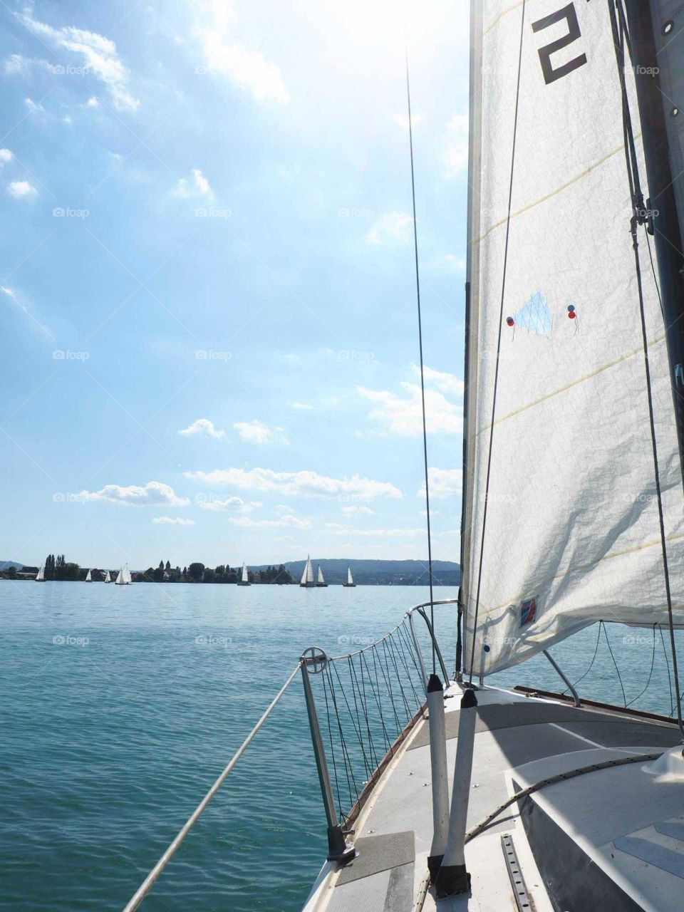 View from the sailing boat on the blue lake on a sunny day.