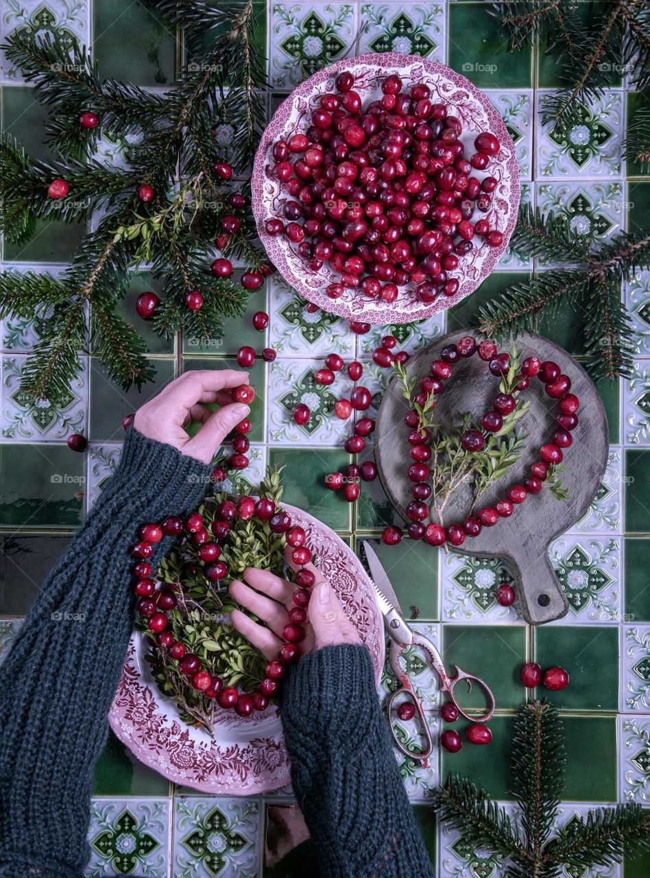 a girl makes hearts from cranberries on a wire against the background of a green tiled table, do-it-yourself scenery for valentine's day