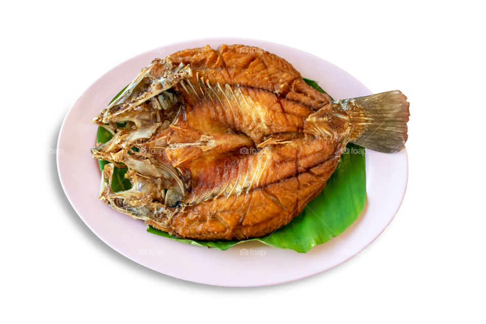 Isolated fried snapper fish on Banana leaves in dish on a white background with clipping path.
