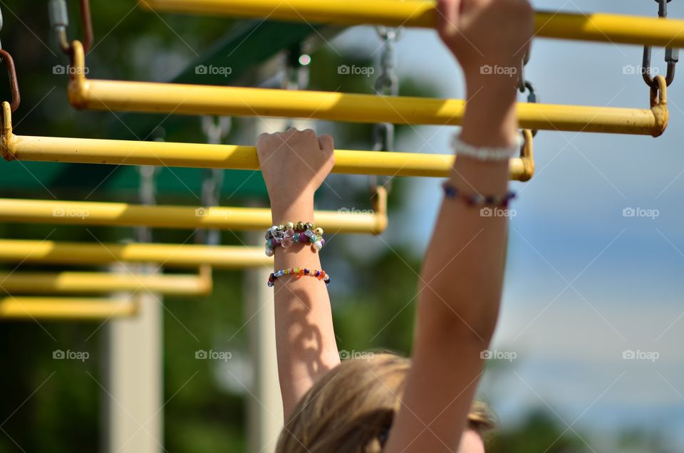 A young girl swinging on the monkey bars at the playground 