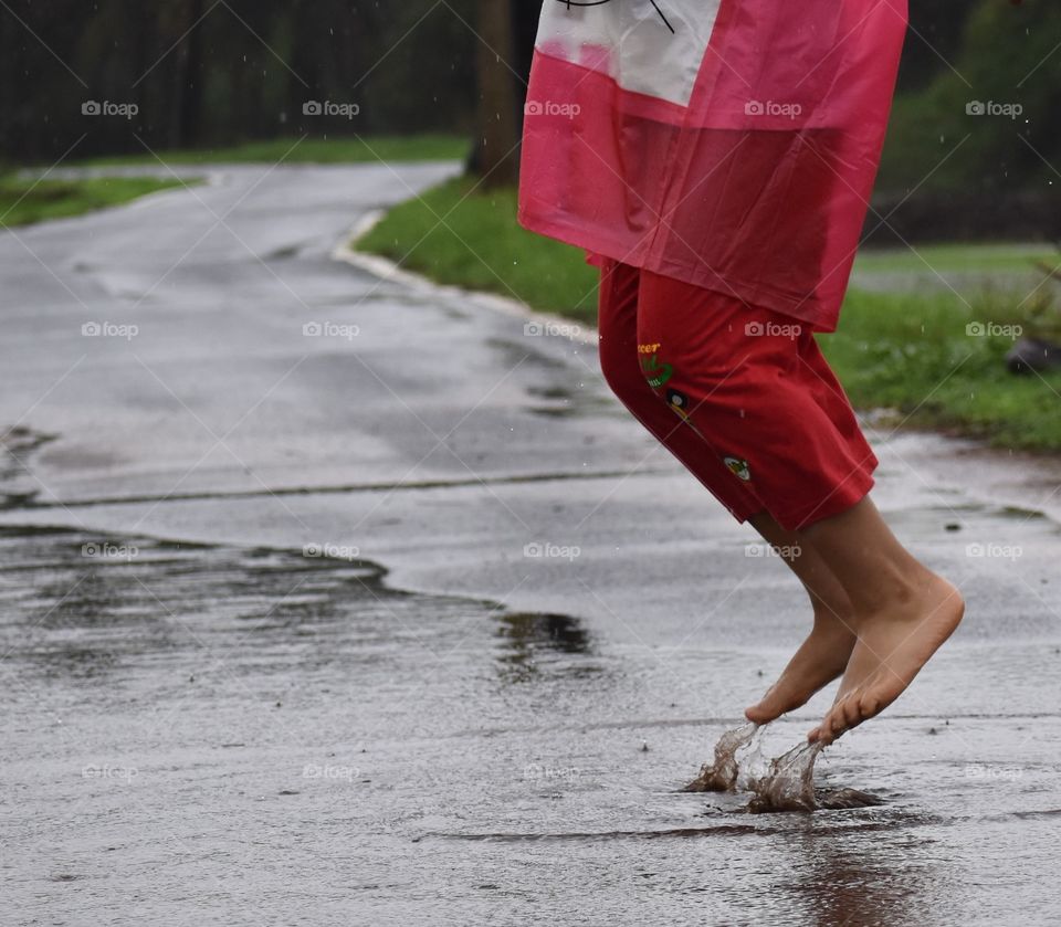 boy jumping inside a puddle of rain water on the street in monsoon 🙂