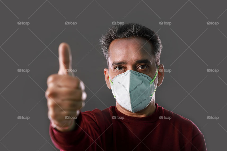 Indian man with thumbs up wearing a protection mask