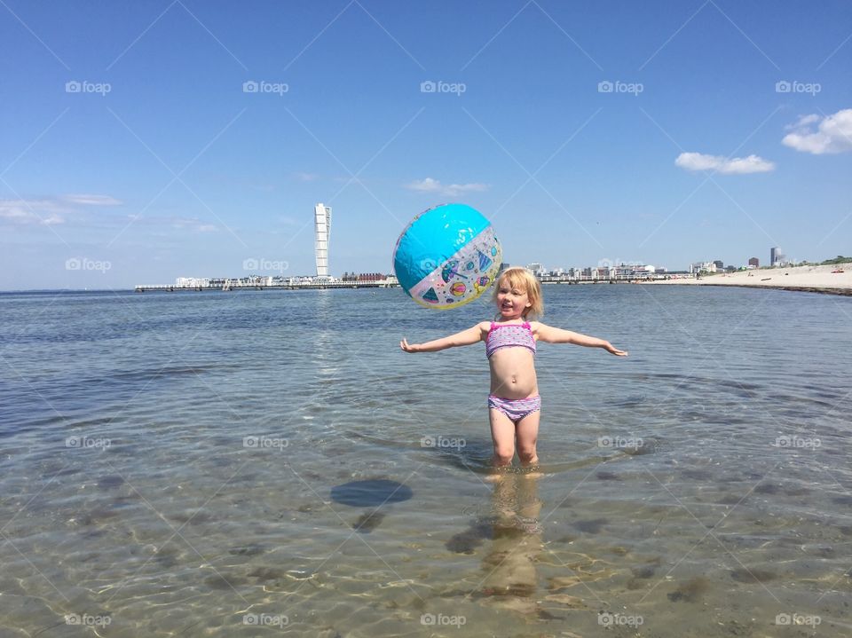 Little girl of three plays with a ball at Ribban beach in Malmö Sweden.