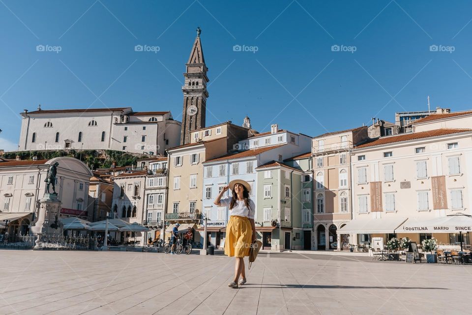 Young woman wearing summer clothes and sunhat exploring the beautiful town of Piran in Slovenia during summer