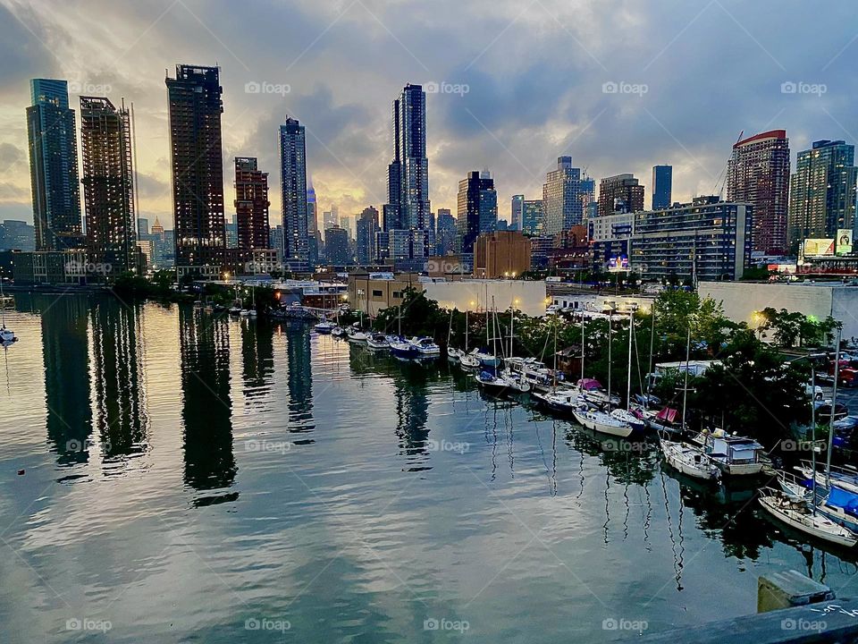 This is the grandiose view from the “Pulaski Bridge” onto “Newtown Creek” with its many kinds of boats that are tied to the shore here from sailboats to houseboats. The experience is especially magical at twilight. 2023. Hypnotic Productions