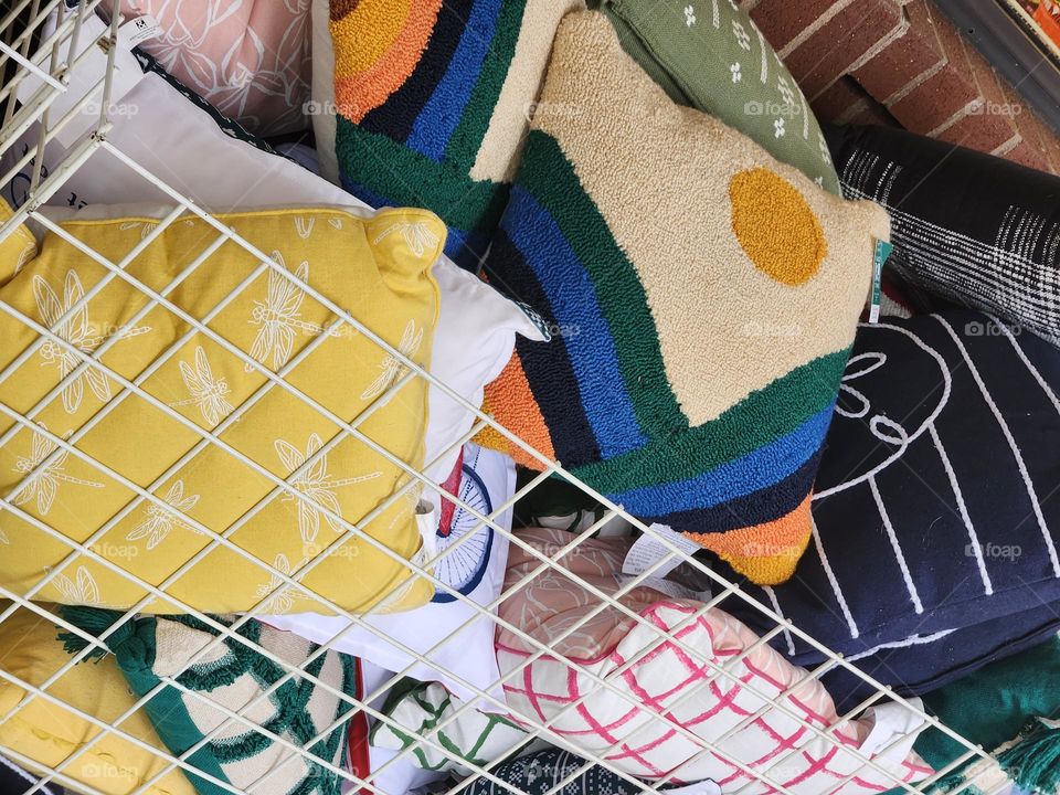 pile of colorful throw pillow in a store bin