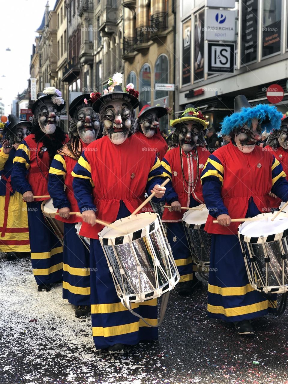a large crowd of people running in the city among large buildings. a crowd of people in masquerade costumes and masks at a fundamental festival in Switzerland. people in bright costumes on a holiday