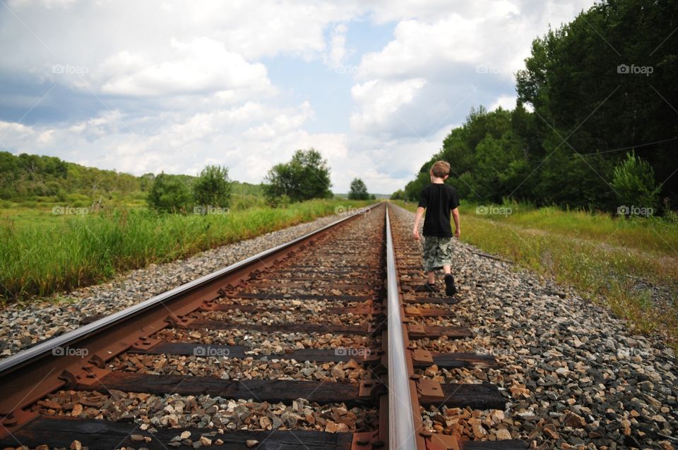 Boy walking down railway 
