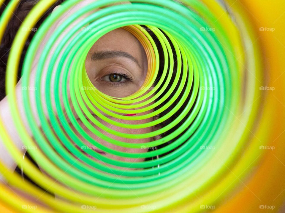 Circle, A Woman Looks through Rainbow Spring Toy