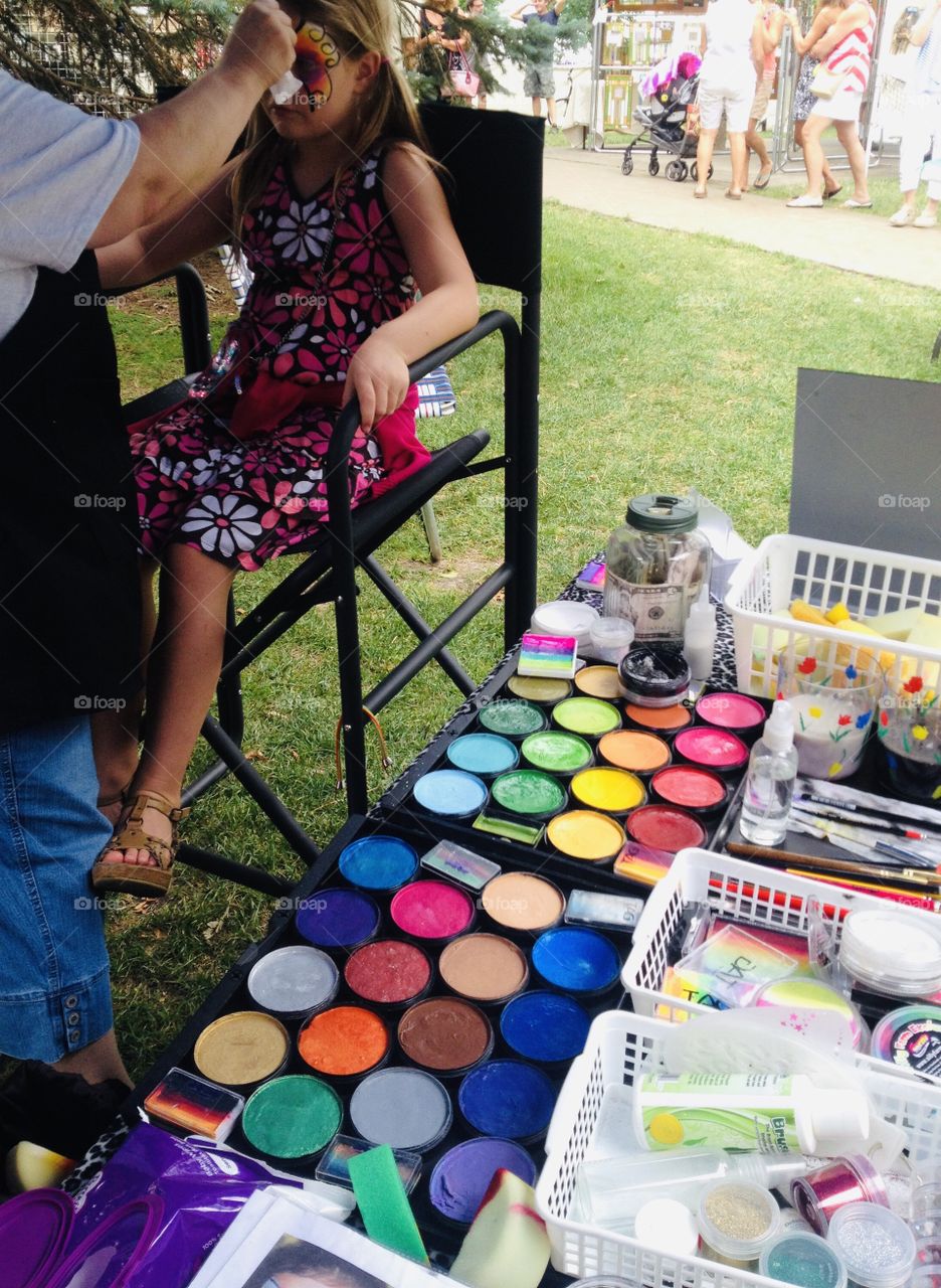 Little girl enjoying getting her face painted at a festival. Look at all the bright colors! 