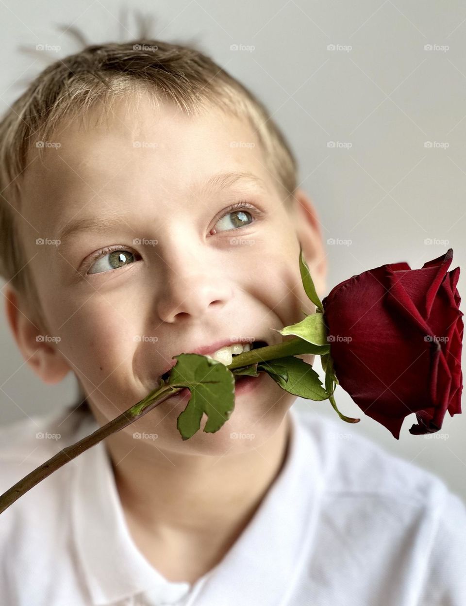 smiling boy with a rose in his mouth