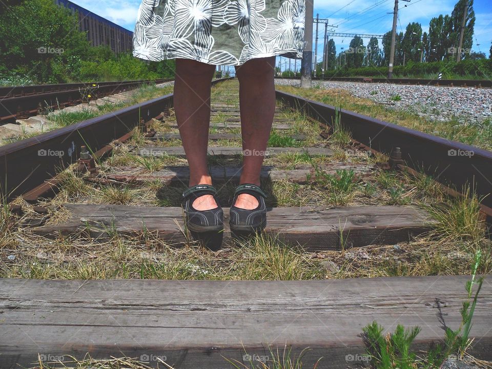 woman's feet on the railroad tracks