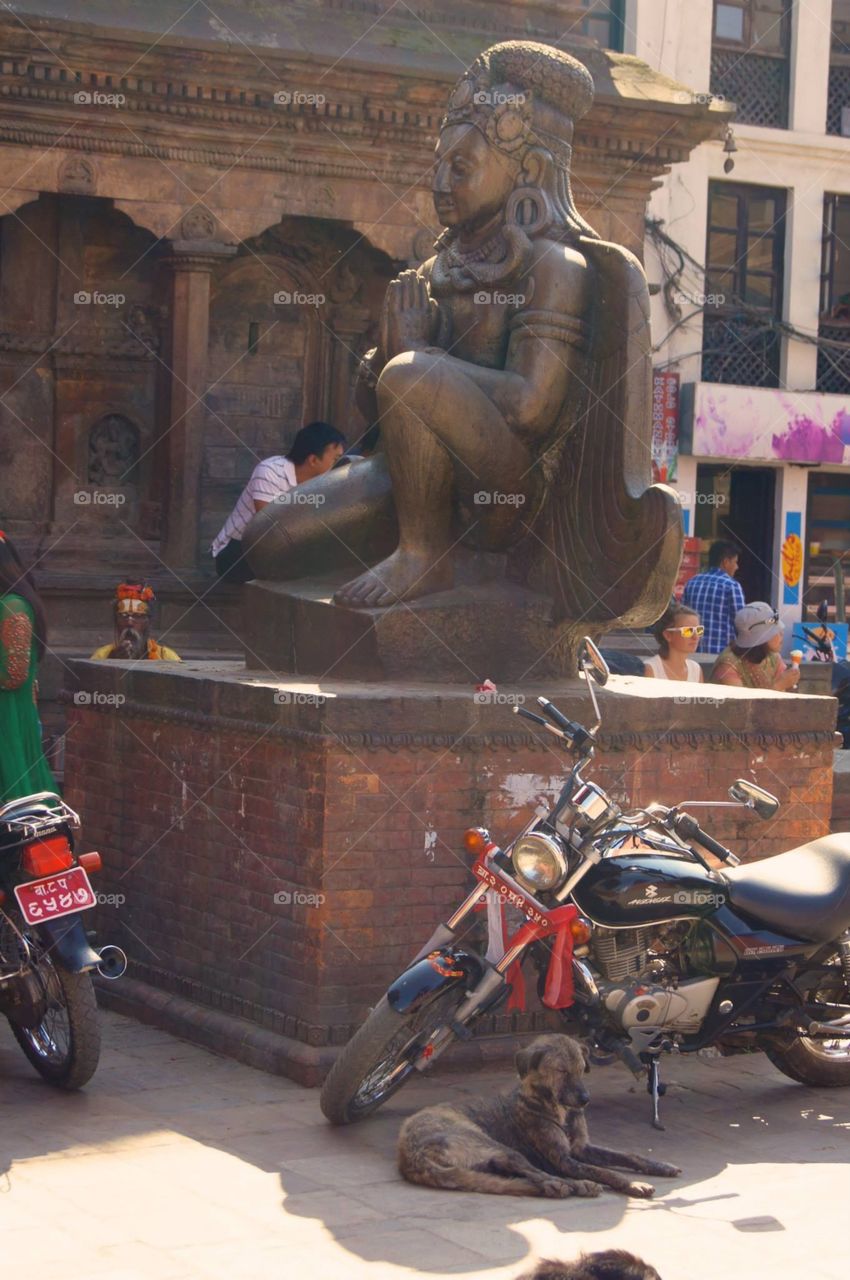 Sitting Statue . A calm street in Nepal . 
