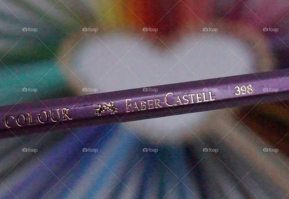 Faber-Castell purple pencil in the foreground with an arrangement of rainbow coloured pencils in the background.