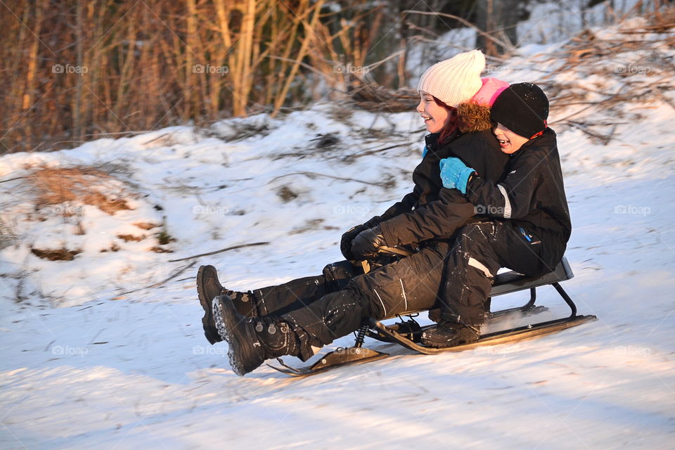 Brother and sister sitting on sledge