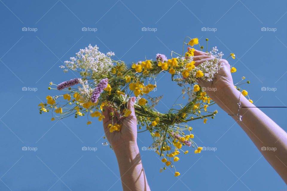 girl holding a wreath of yellow flowers against the sky