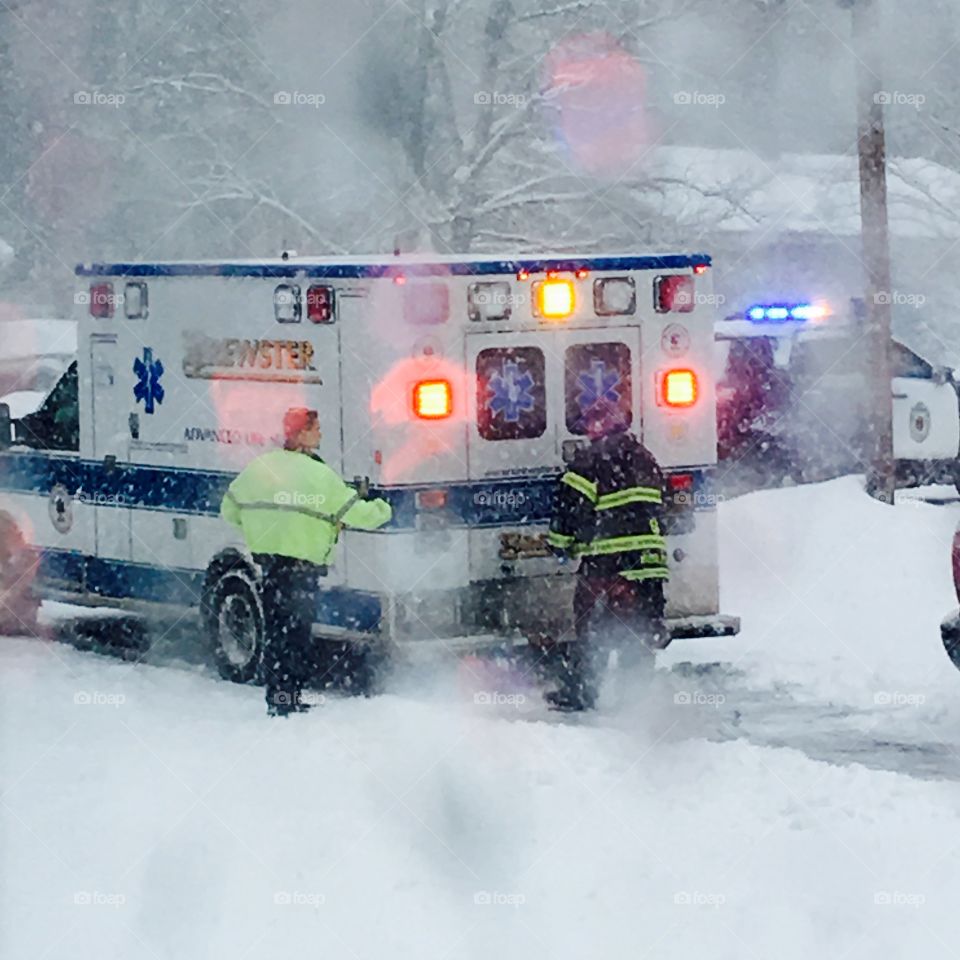 Ambulance in driveway w person inside
on way to hospital while blizzard happening

Fireman & policeman are closing doors of ambulance as the sirens sound; lights flash and traffic is being stopped. The patient is in a medical situation on way to hospital!