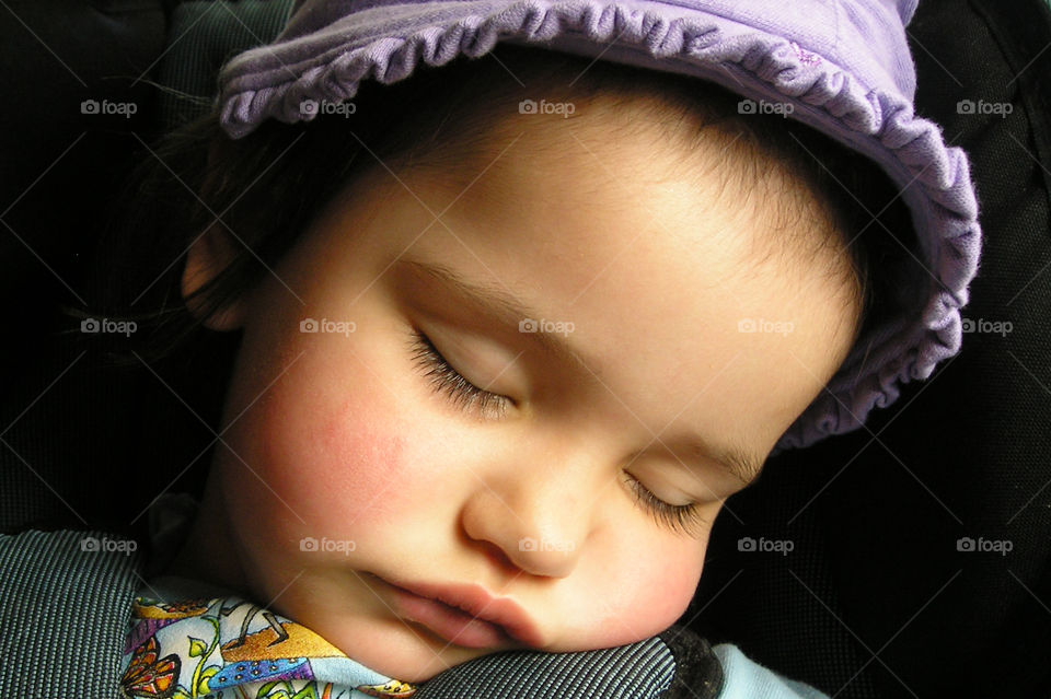 A closeup of the rosy-cheeked sleeping face of my daughter. She is in in her car seat and fell asleep on the way home from a long playdate with mom at the beach. The sun was shining on her face and she looked so beautiful, peaceful and angelic. 