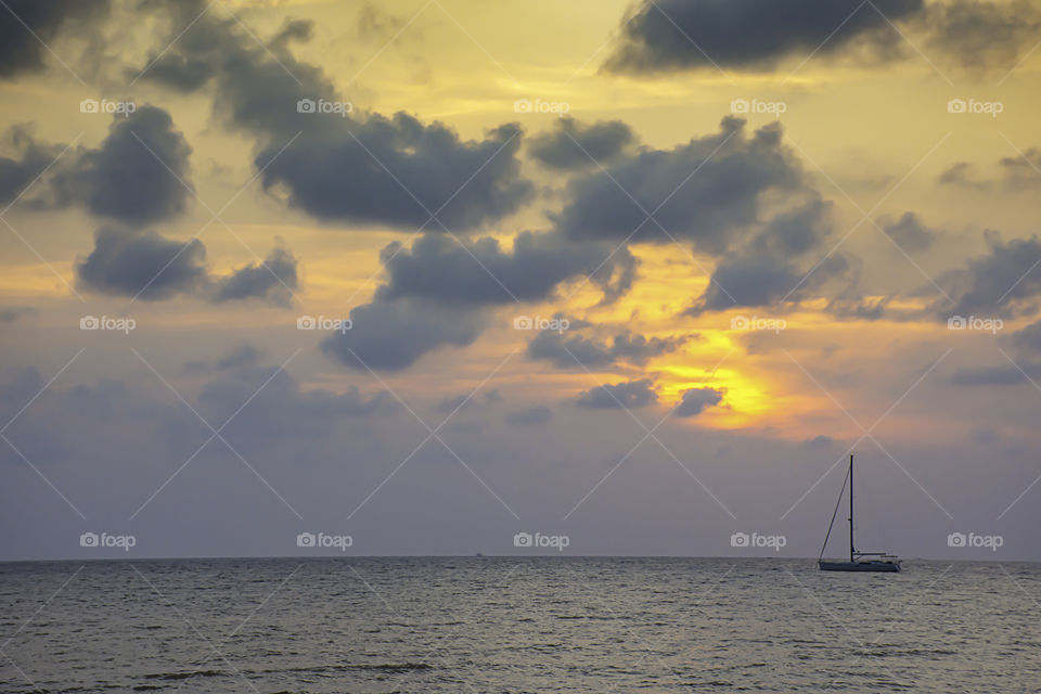 Yacht parked in the sea and the sun behind the clouds in the evening.