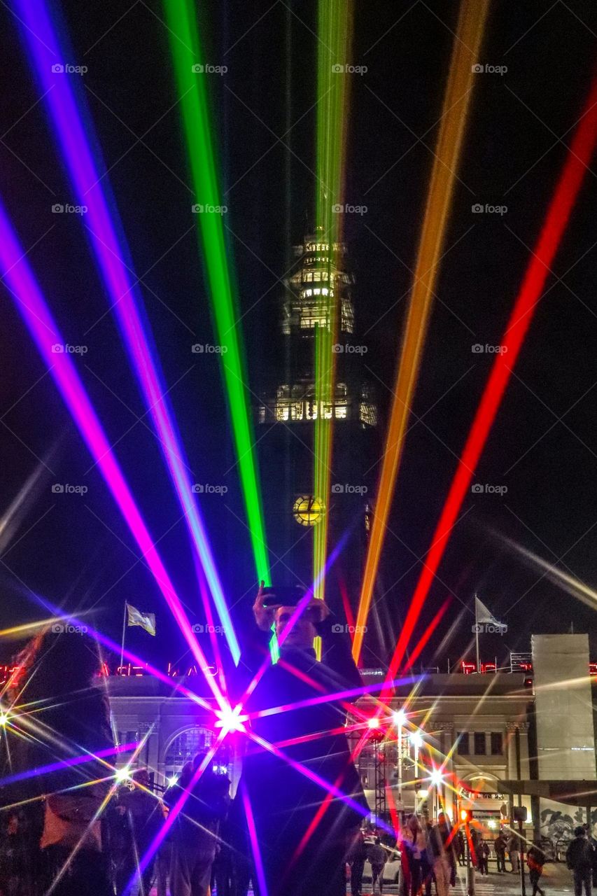 San Francisco Pride 2023 laser light display of the pride flag colors illuminating the sky in front of the Ferry Building on the Embarcadero