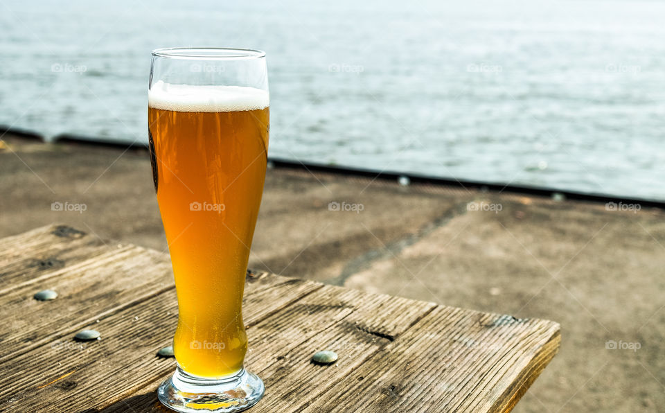 a glass of beer, standing on a wooden table on the quay of ferries on the Elbe