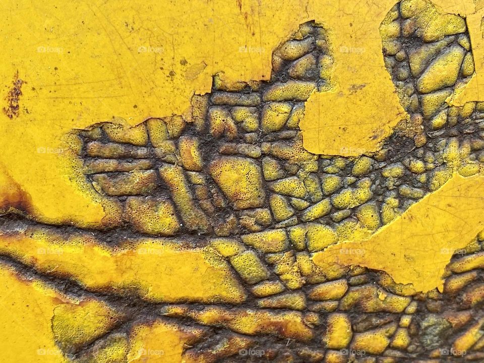 Rust and scratches on a piece of yellow painted metal