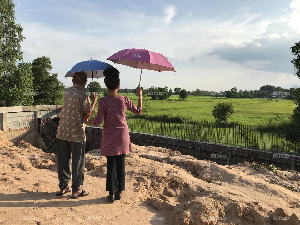 My grandpa and my mom came on construction site but seem the focused on green field beyond the wall instead 