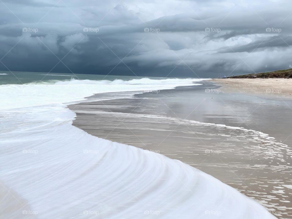 Atlantic Ocean Beach With Time In Motion Long Exposure Of The Waves On The Seashore During A Thunderstorm With Dark Grey Clouds.