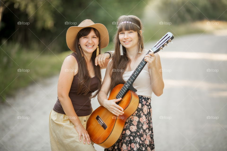 Young beautiful bohemian style women with guitar on the road