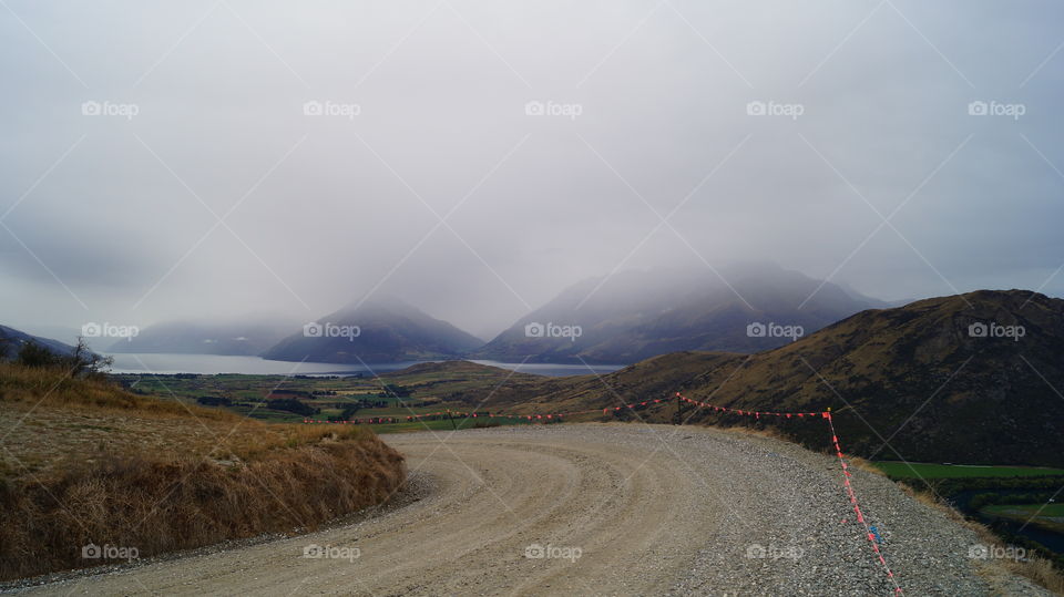 Empty road with river and foggy mountain