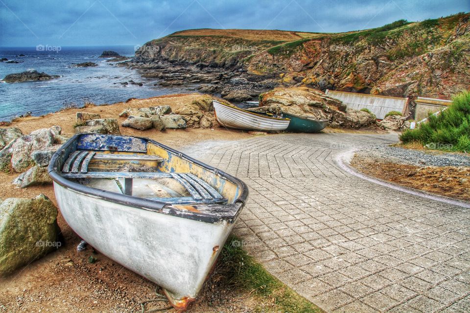 Old Fishing Boats. Disused fishing boats sit next to a slipway with the ocean and cliffs behind.