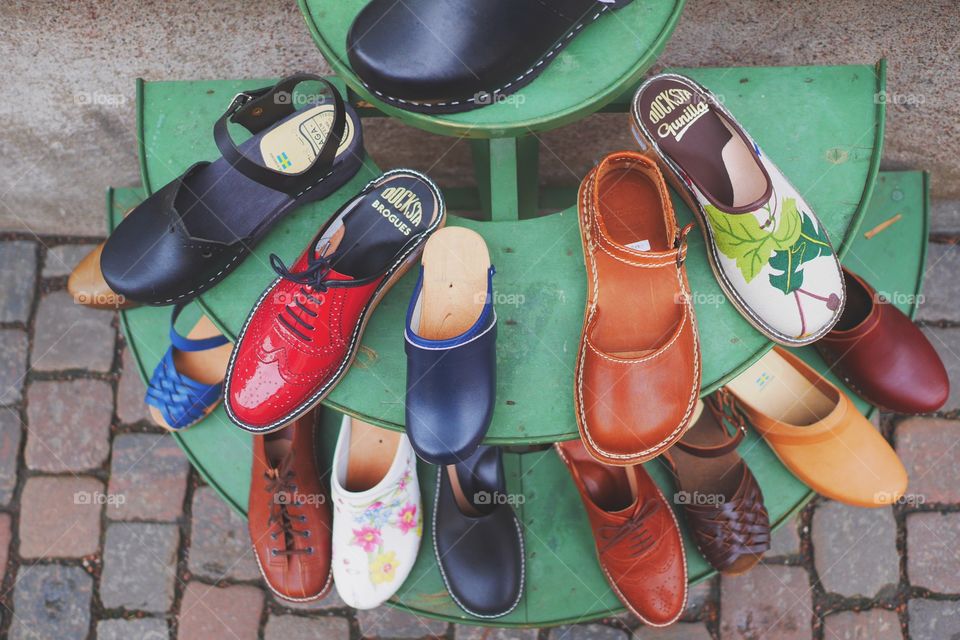 Lots of different kinds of shoes on a shoe stand out on the pebbled street