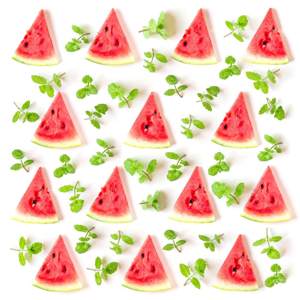 Juicy watermelon slices with fresh mint leaves, creative flatlay pattern. Summertime fun.