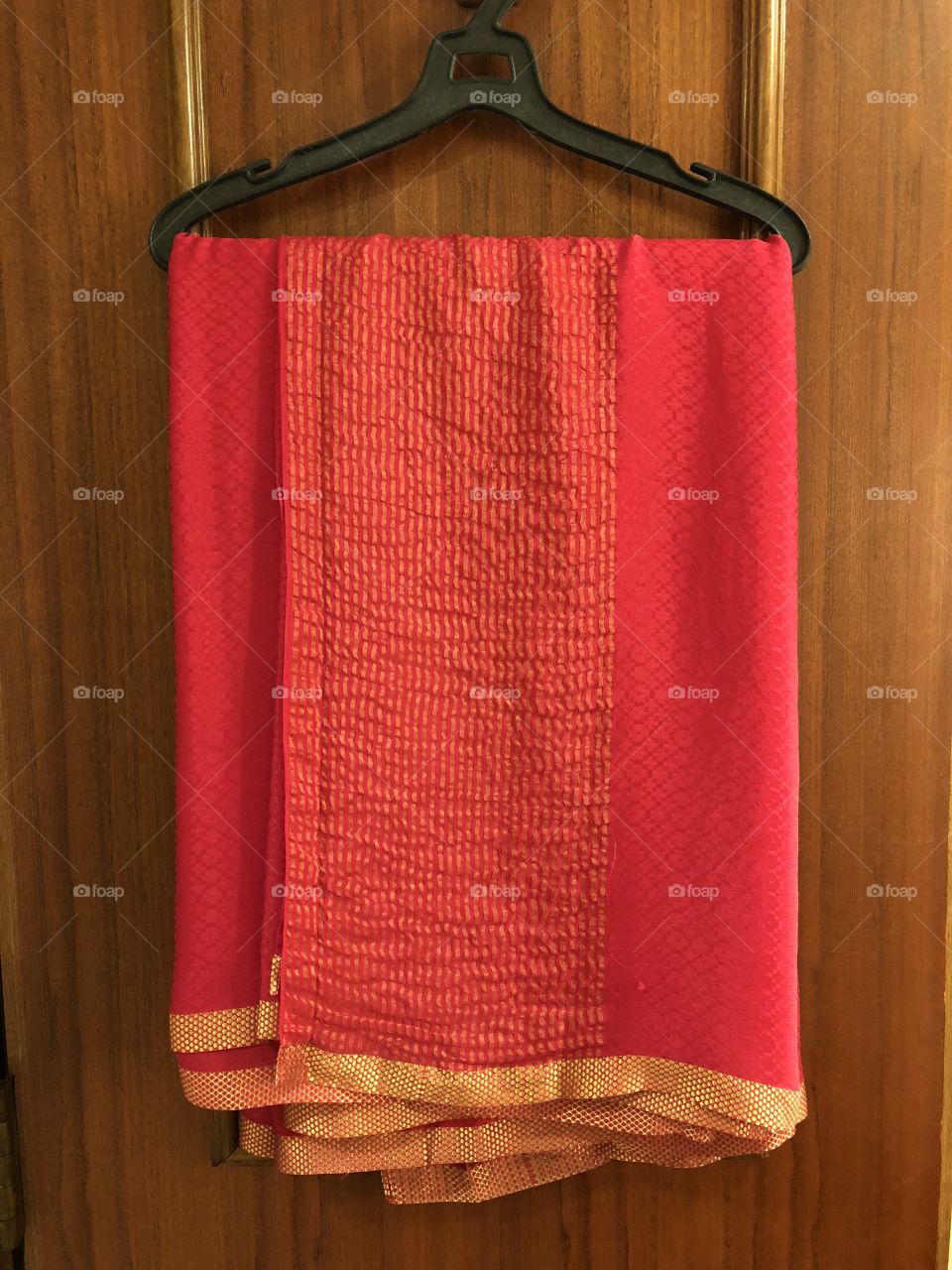 Pink saree draped on a hanger. Long garment with gold accent edging. Indian silk material. 2018.